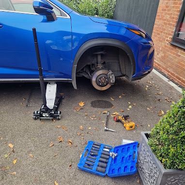 Blue car with wheel removed during tyre replacement