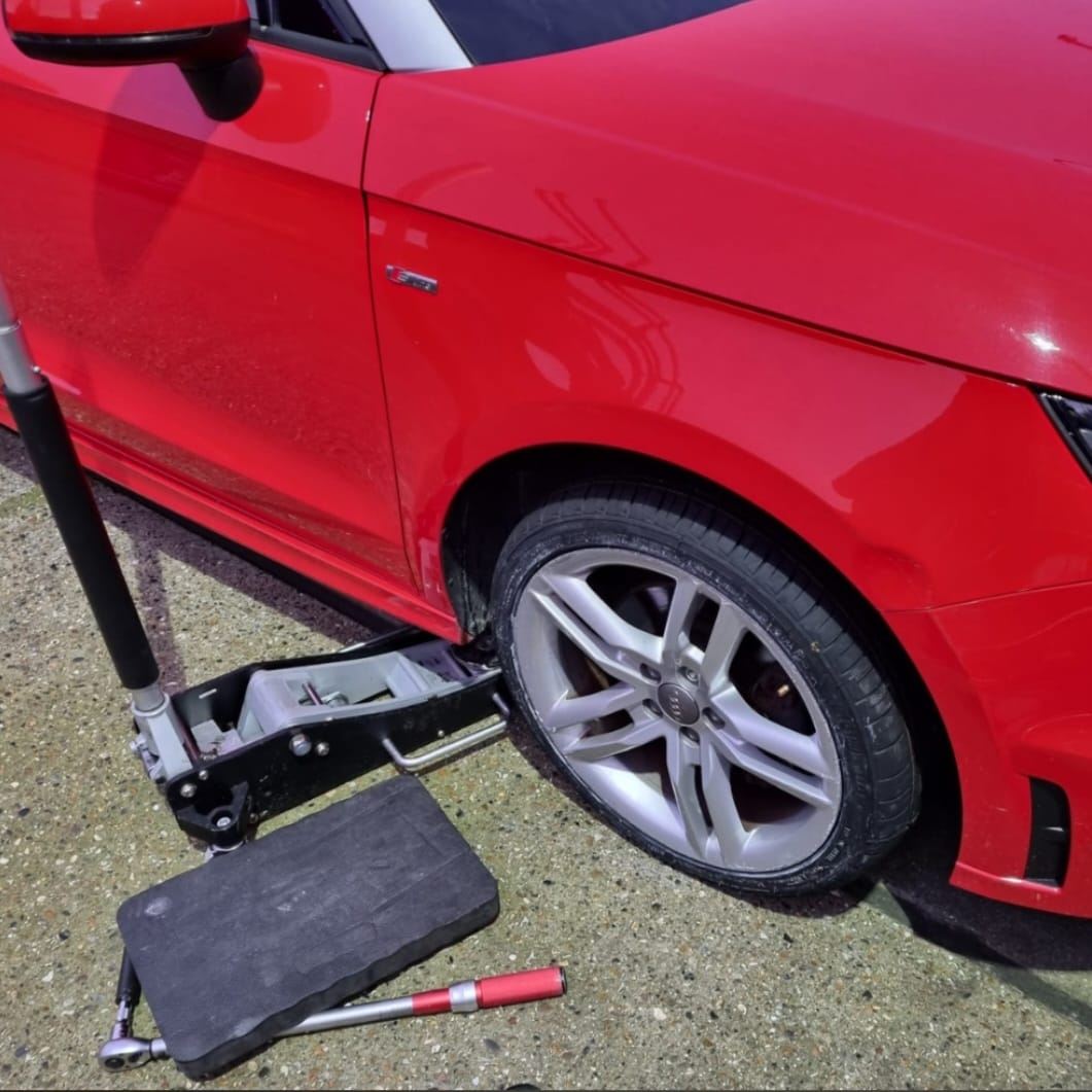 Red car being serviced with a hydraulic jack
